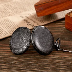 Detailansicht einer schwarzen Vintage-Taschenuhr mit floraler Gravur auf rustikalem Holz