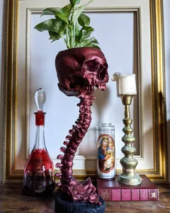 Détail d'un pot de fleurs crâne rouge gothique sur un support de colonne vertébrale