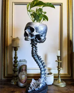Vue détaillée d'un pot de fleurs en forme de crâne argenté avec un support de colonne vertébrale.