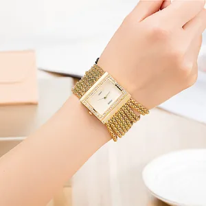 Detalle elegante de un reloj cuadrado dorado para mujer con cristales en la muñeca