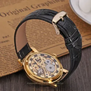 Detail view of a luxury gold skeleton mechanical watch with a black leather strap.