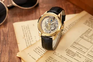 Detail view of gold-tone men's skeleton watch with transparent hollow dial on vintage paper.