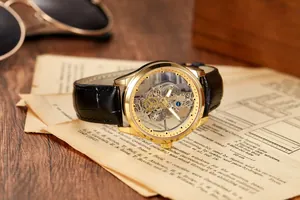 Detailed close-up of a golden skeleton automatic watch movement with black leather strap