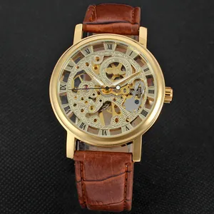 Close-up of Winner skeleton mechanical watch with gold case and brown leather strap.