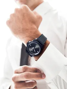 Gedetailleerde opname van een strak TOMI herenhorloge met een zwarte leren band op een model