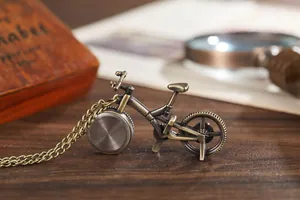 Close-up of a vintage bronze bicycle-shaped quartz pocket watch on a wooden table.