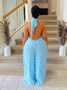 Back view of a woman in a sky blue halter backless jumpsuit with textured fringe detail