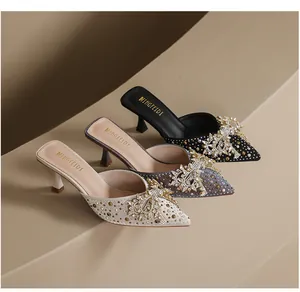 Detail van elegante spitse muiltjes met strasstrikjes en kittenhakken in drie kleuren.