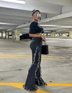 Dettaglio jeans svasati neri con bordi sfrangiati consumati e stile streetwear vintage