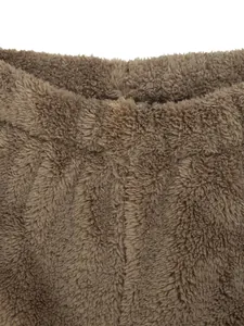 Gros plan sur la texture du tissu en peluche marron doux de ce pantalon de détente d'hiver.