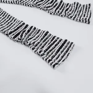 Dettaglio macro dei pantaloni in maglia a righe a vita alta con bordo sfilacciato