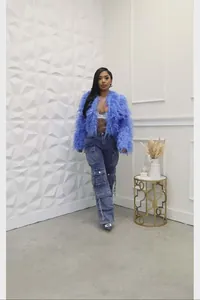 Scatto a figura intera di una modella con giacca corta blu in eco-pelliccia e jeans