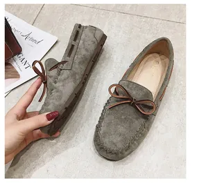 Nahaufnahme grauer Wildleder-Loafer für Damen mit stilvoller brauner Schleifenverzierung