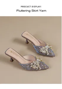 Gedetailleerd zijaanzicht van elegante muiltjes met kittenhak en een grote strik van strassteentjes