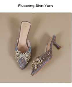 Detailweergave van elegante muiltjes met puntige neus en een fonkelende strasstrik.