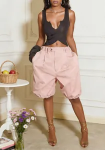 High-waisted light pink balloon shorts for women styled with a black top in a studio