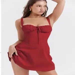 Robe courte sexy rouge évasée avec détail à nouer et fines bretelles sur mannequin.