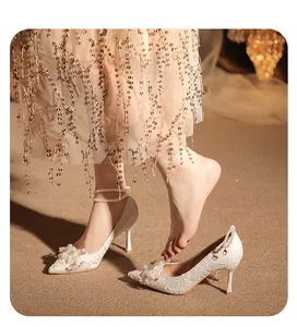 Elegantes tacones de novia en encaje blanco con flores y correas de perla al tobillo
