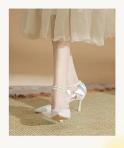 Elegant white satin high heels with double pearl ankle straps and bow detail