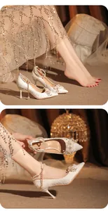 Detalle exquisito de tacones de novia blancos con correa de perlas y flores decor.