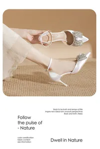 Detail view of elegant white stiletto heels with sparkling rhinestone bow decoration.