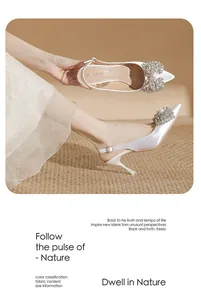 Detail view of elegant white satin pointed-toe stiletto heels with rhinestone flower