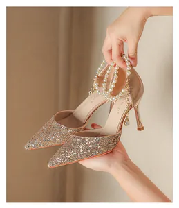 Close-up of champagne glitter pointed-toe high heels with elegant double pearl ankle straps.