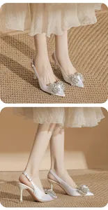 Detail of elegant white pointed-toe stiletto pumps with sparkling rhinestone bows