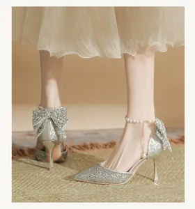 Elegant detail of silver glitter bridal high heels with pearl ankle strap and bow