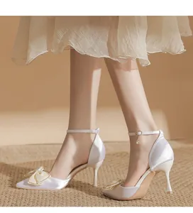 Elegante spitze High Heels mit Satin-Finish, Schleifendetail und Knöchelriemen am Fuß getragen