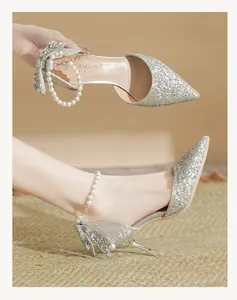 Detailed view of elegant silver glitter high heels with pearl ankle straps for bridal wear.