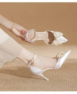 Elegante perlweiße spitze High Heels mit Satinschleife und schlankem Knöchelriemen.