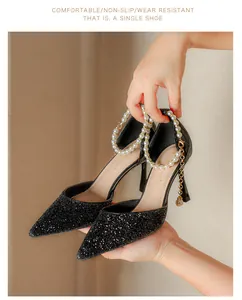 Detail of black glittery pointed-toe high heels with elegant pearl ankle straps.