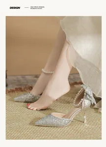 Elegant detail of silver sequined bridal pumps with pearl ankle straps and glitter bow