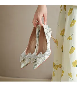 Detailed view of elegant French stiletto pumps with mesh bow and glitter accents.
