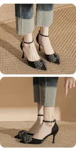 Side view of black pointed stiletto heels with a sparkling crystal bow detail.
