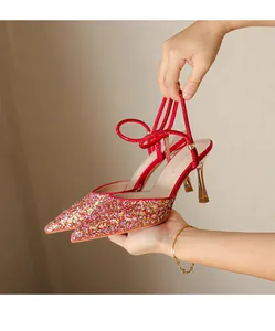 Close-up of red glitter pointed-toe high heels with dainty straps and gold stiletto heels.