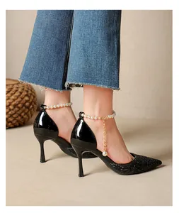 Close-up of elegant black glitter pointed-toe stiletto pumps with pearl strap