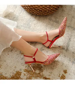 Close-up view of elegant red glitter pointed-toe high heels with thin gold stiletto.