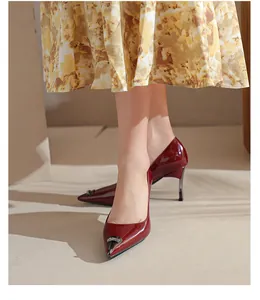 Close-up view of elegant burgundy patent leather pointed-toe high heels on model's legs.