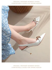 Détail élégant d'escarpins slingback en cuir verni blanc avec boucle mors dorée chic