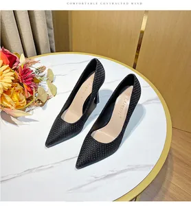 Elegant black woven pointed-toe stiletto high heel pumps displayed on a marble table with flowers