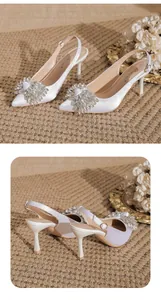 Detailed view of white satin pointed-toe stiletto heels with crystal bow accent