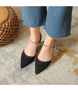 Close-up of elegant black pointed-toe glitter heels with rhinestone ankle straps.