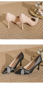 Dettaglio di décolleté a punta con tacco a spillo in beige e nero e fibbie di strass.