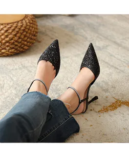 Detail view showing black glitter pointed-toe high heels with rhinestone ankle straps