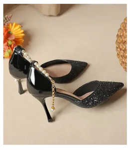 Detail of black pointed toe heels featuring glitter finish and elegant pearl ankle chain.