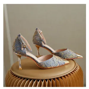 Close-up of blue textured pointed high heels with gold metal cap and ankle strap