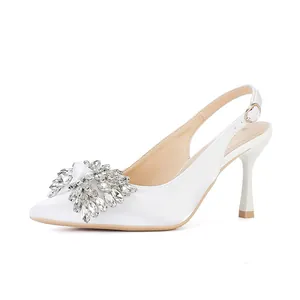Side view of white pointed-toe pumps with sparkling rhinestone crystal bow detail.