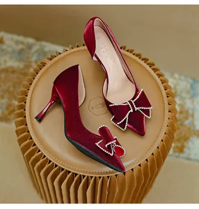 Dettaglio elegante di décolleté in raso bordeaux con punta e fiocco di strass lucido